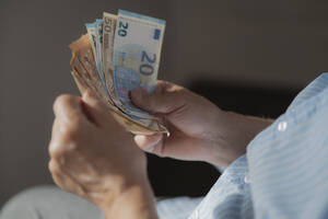Hands of senior man counting European paper Currency - AZF00506