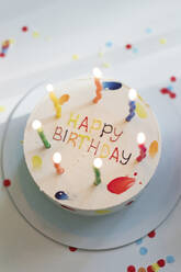 Birthday cake with illuminated candles on table - ONAF00459