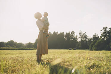 Happy mother with son enjoying nature on sunny day - NDEF00426