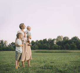 Loving mother with children standing in nature at sunset - NDEF00452