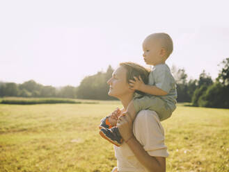 Mother carrying son on shoulders in nature on sunny day - NDEF00454