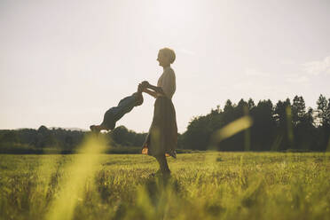 Happy mother spinning son and having fun in nature - NDEF00455