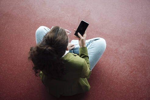 Geschäftsfrau auf dem Boden sitzend mit Smartphone - JOSEF18183