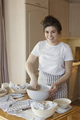 https://us.images.westend61.de/0001813310j/happy-young-woman-mixing-bread-dough-at-home-ONAF00467.jpg