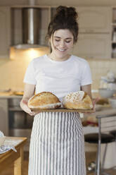 Glückliche Frau mit frisch gebackenem Brot in der Hand - ONAF00475