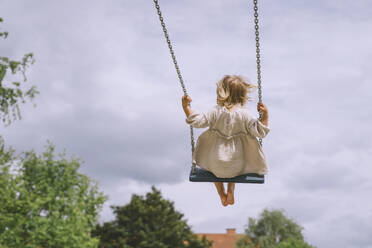 Girl swinging on swing in front of sky - NDEF00457