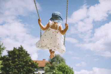 Girl swinging on swing in front of cloudy sky - NDEF00458