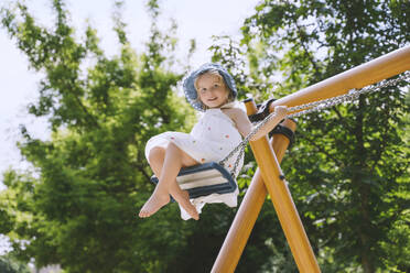 Smiling girl swinging on swing at park - NDEF00459