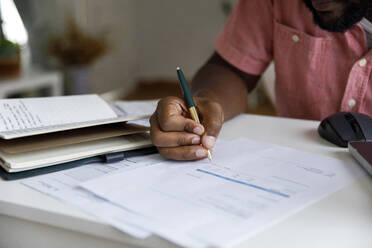 Freelancer calculating bills at desk in home - IKF00007