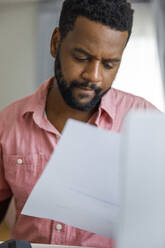 Freelancer reading financial bills at home - IKF00011