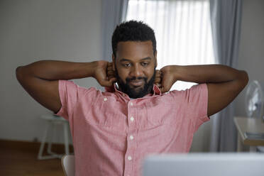 Tired freelancer stretching arms at home office - IKF00012