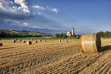 Italienische Landschaft mit einem Feld voller Heuballen und einer Kirche im Hintergrund, Emilia Romagna, Italien, Europa - RHPLF23691