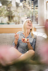 Happy woman eating fresh bowl of fruits at home - JOSEF18248