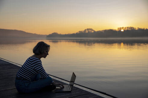 Freiberufler bei der Arbeit am See am Morgen - FLLF00868