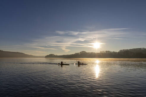 Silhouette von Kanufahrern, die bei Sonnenaufgang auf einem See paddeln - FLLF00874