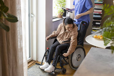 Woman with paraplegia adjusting wheelchair at home - MASF36114