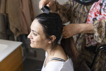 Mutter kämmt die Haare ihrer querschnittsgelähmten Tochter im heimischen Badezimmer - MASF36120