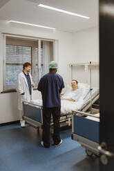 Lächelnder männlicher Patient im Gespräch mit medizinischem Personal im Krankenhaus - MASF36205