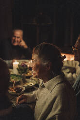 Side view of happy senior woman enjoying candlelight dinner party - MASF36219