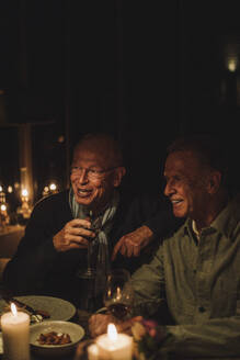 Glückliche ältere männliche Freunde genießen ein gemeinsames Abendessen bei Kerzenlicht auf einer Party - MASF36226