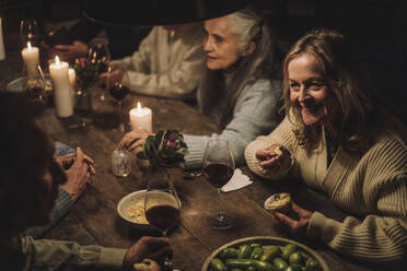 Smiling senior woman eating cupcake while talking to friend during party - MASF36230