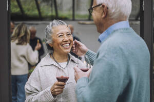 Älterer Mann berührt das Gesicht einer glücklichen Freundin bei einer Dinnerparty - MASF36246