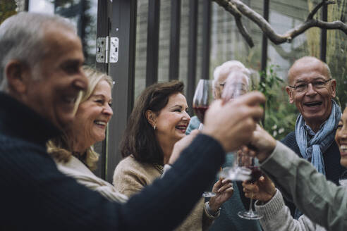 Fröhliche männliche und weibliche Freunde im Ruhestand stoßen bei einer Dinnerparty auf Getränke an - MASF36252