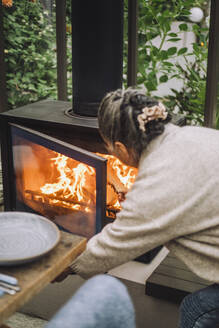 Ältere Frau legt während einer Dinnerparty Brennholz in den Kamin - MASF36267