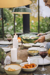 Ein älterer Mann deckt den Tisch für eine Dinnerparty - MASF36269