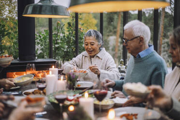 Ältere Frau serviert einem männlichen Freund bei einer Dinnerparty Essen - MASF36272