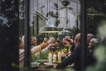 Happy senior male and female friends toasting wine during dinner party in backyard - MASF36277