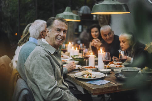 Portrait of happy senior man with friends during dinner party - MASF36286