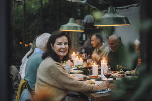 Porträt einer lächelnden älteren Frau, die sich mit Freunden bei einer Dinnerparty amüsiert - MASF36289
