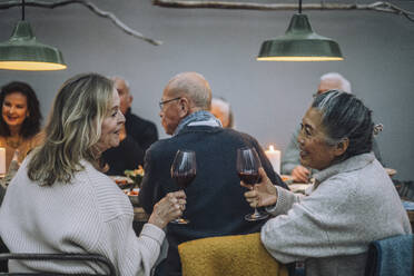 Senior women with wineglasses talking to each other at dinner party - MASF36293