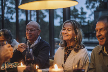 Lächelnde ältere Frau mit männlichen Freunden im Ruhestand während einer Dinnerparty - MASF36300