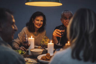 Lächelnde Frau im Ruhestand genießt das Abendessen mit Freunden auf einer Party - MASF36302