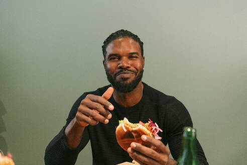 Portrait of smiling man eating burger at restaurant - MASF36336