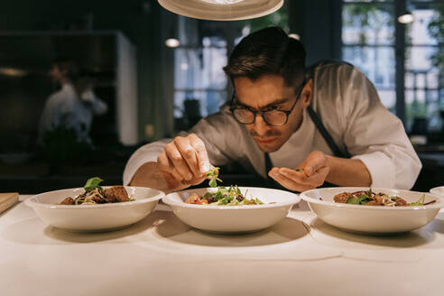 Male chef plating food in plate while working in commercial kitchen - MASF36348