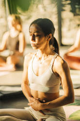 Junge Frau mit Händen auf dem Bauch übt Yoga im Retreat Center - MASF36366