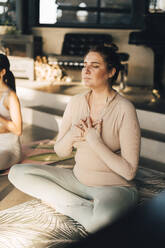 Frau meditiert mit den Händen auf der Brust im Schneidersitz im Retreat Center - MASF36436