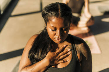 Plus size woman with hand on chest practicing breathing exercise at retreat  center stock photo
