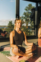 Woman sitting cross-legged doing meditation at retreat center - MASF36456