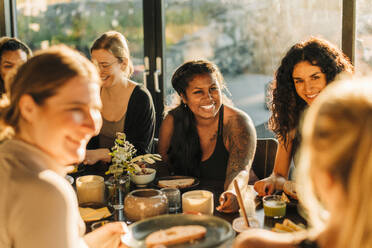 Fröhliche Frau unterhält sich mit Freundinnen beim Frühstück im Freizeitzentrum - MASF36461
