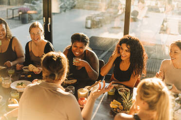 Multirassische Freundinnen, die sich beim Frühstück im Freizeitzentrum unterhalten - MASF36463