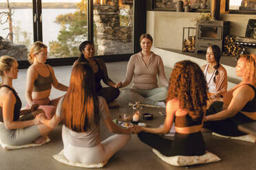 Multiracial female friends meditating together while sitting on floor at retreat center - MASF36509