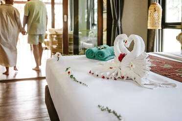 Schwan Handtücher auf dem Bett mit Mitte Erwachsenen Paar im Hintergrund im Hotelzimmer - MASF36537