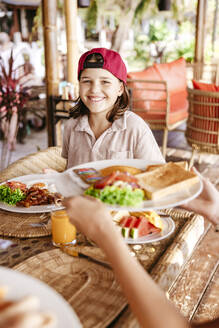 Porträt eines lächelnden Mädchens mit Frühstück auf dem Tisch in einem Touristenort im Urlaub - MASF36548