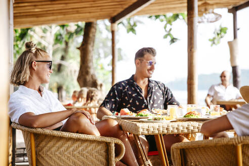 Lächelndes heterosexuelles Paar am Tisch sitzend beim Frühstück im Resort - MASF36555