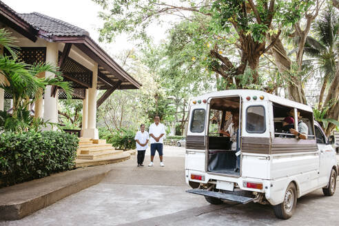Männliche und weibliche Besitzer schauen sich Touristen an, die in einem Van am Urlaubsort sitzen - MASF36557