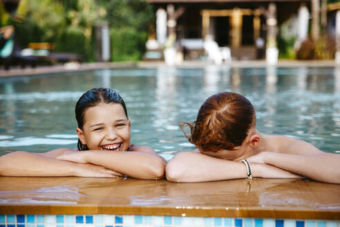 Glückliches Mädchen mit Bruder im Schwimmbad im Urlaub genießen - MASF36563